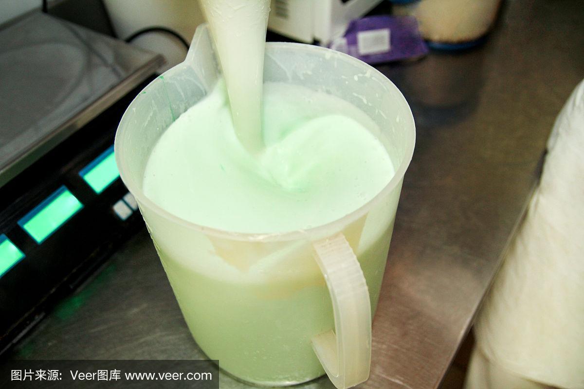 女厨师兼工作人员在冰淇淋工厂,她混合牛奶,薄荷提取物和香精,准备